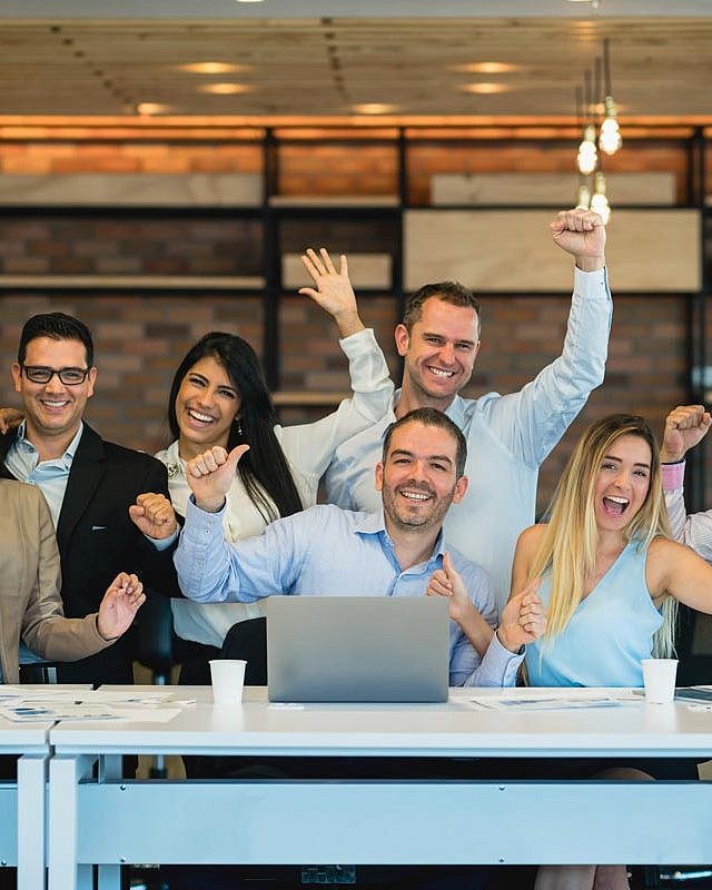 Eine Gruppe glücklicher und motivierter Arbeitskolleg*innen im Büro