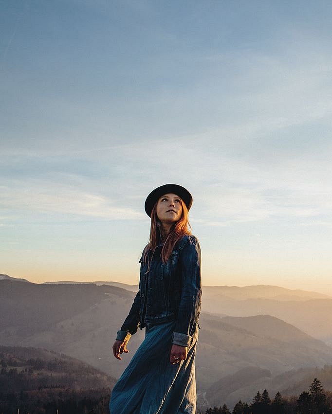 Eine junge Frau mit einem Hut auf wandert durch die Berge.